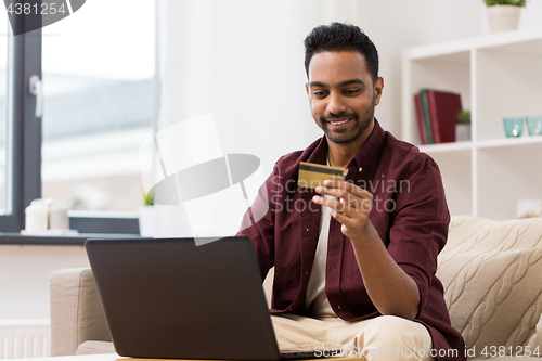 Image of smiling man with laptop and credit card at home