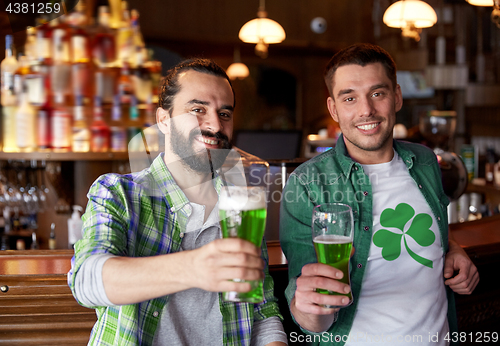 Image of male friends drinking green beer at bar or pub