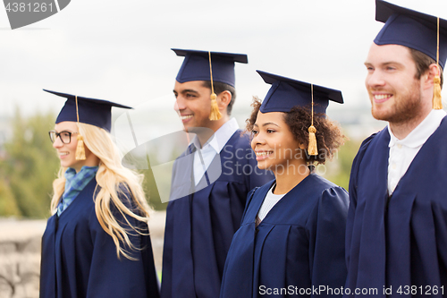 Image of happy students or bachelors in mortar boards