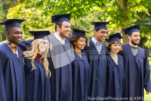 Image of happy students or bachelors in mortar boards