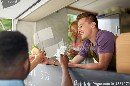 Image of happy salesman selling hamburgers at food truck