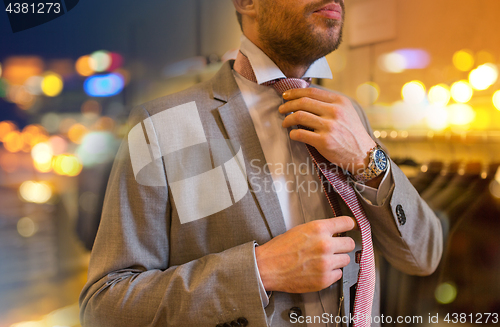 Image of close up of man tying tie at clothing store