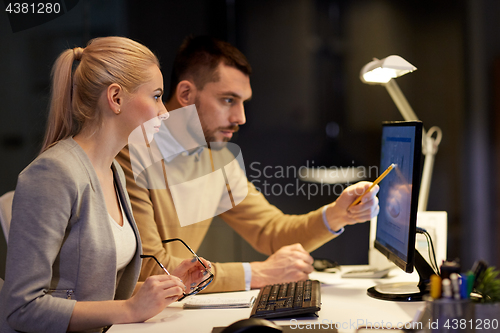 Image of business team with computer working late at office