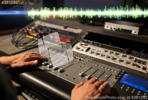 Image of hands on mixing console at sound recording studio