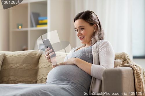 Image of happy pregnant woman with smartphone at home