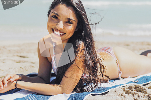 Image of Charming model lying on beach smiling at camera
