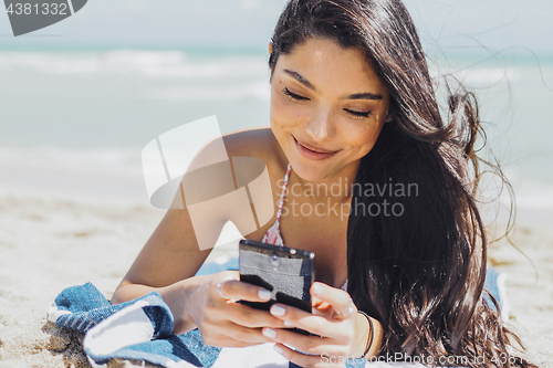 Image of Pretty girl using phone on beach