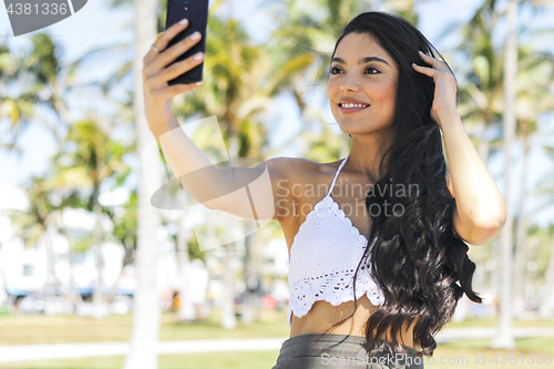 Image of Trendy brunette taking selfie in sunshine