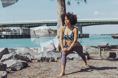 Image of Black sportive girl warming up in park