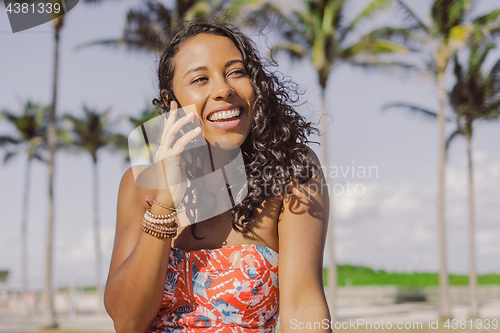 Image of Pretty ethnic woman talking on smartphone in summertime