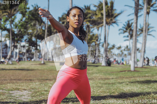 Image of Relaxed sportive woman training in sunny park