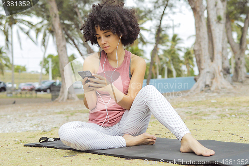 Image of Chilling black girl using phone on mat