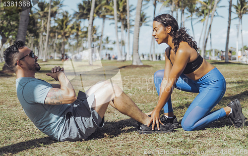 Image of Woman helping man with exercise in park