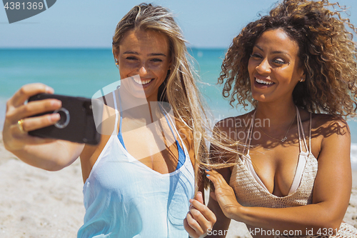 Image of Cheerful diverse women taking selfie on beach