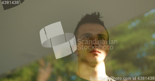 Image of reflection of sad man looking through window