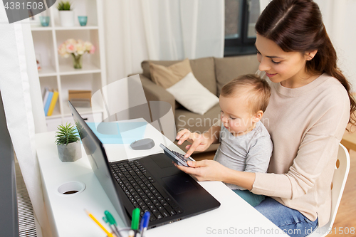 Image of happy mother with baby and laptop working at home