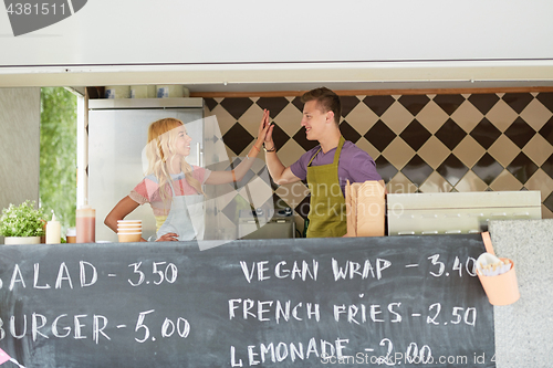 Image of couple of sellers making high five at food truck