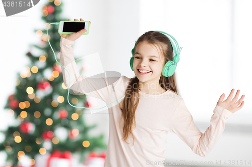 Image of girl with smartphone and headphones at christmas