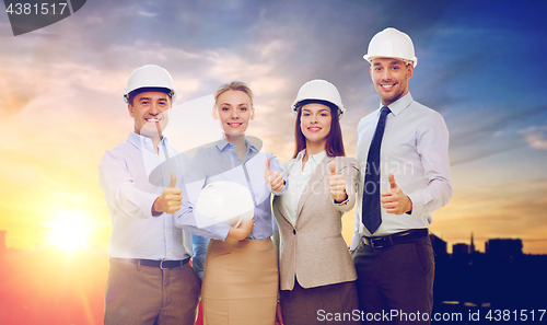 Image of business team in white hard hats showing thumbs up