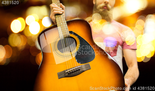 Image of close up of musician with guitar over night lights