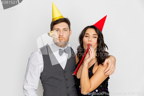 Image of happy couple with party blowers having fun