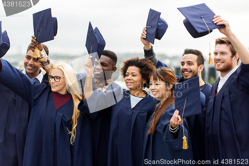 Image of happy graduates or students waving mortar boards