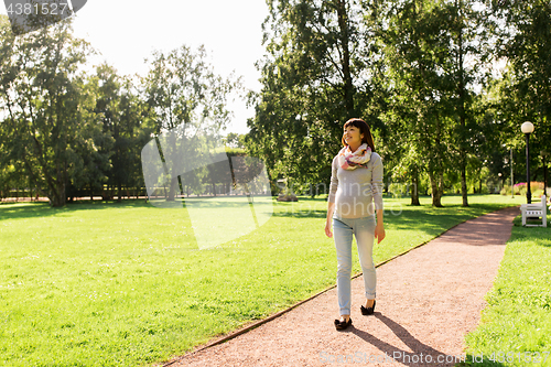 Image of happy pregnant asian woman walking at park