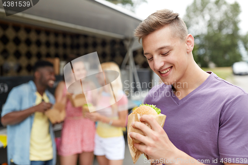 Image of happy man with hamburger and friends at food truck