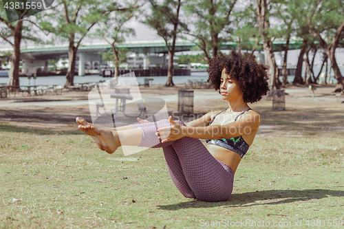 Image of Girl practicing abdomen muscles on meadow