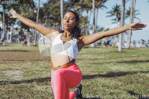 Image of Relaxed black woman doing exercise in park