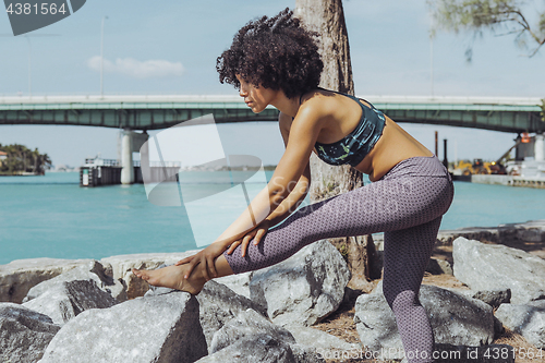 Image of Black girl working out on riverbank
