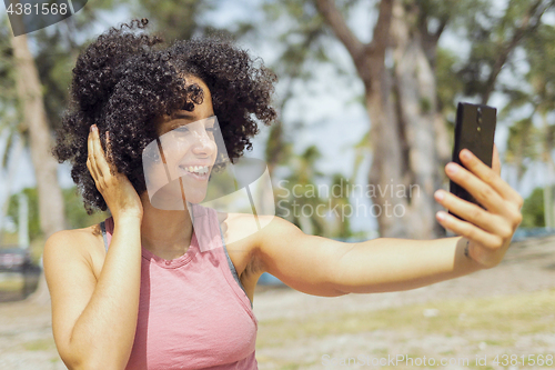 Image of Laughing young girl taking selfie in park