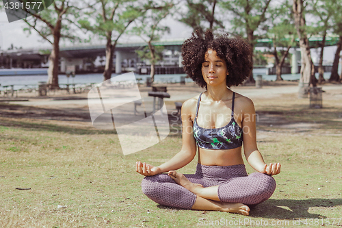 Image of Content woman meditating in sunlight in park