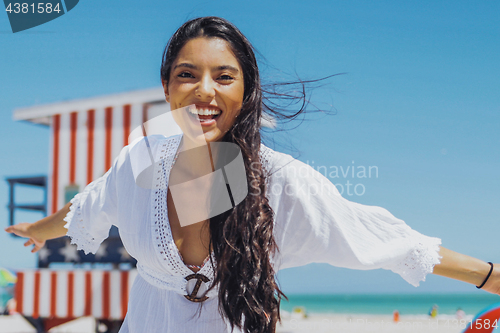 Image of Cheerful ethnic woman laughing on beach