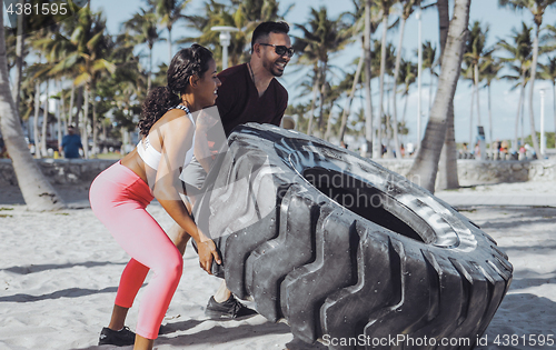 Image of Sportive couple training with tyre together