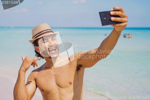 Image of Man gesturing shaka and taking selfie