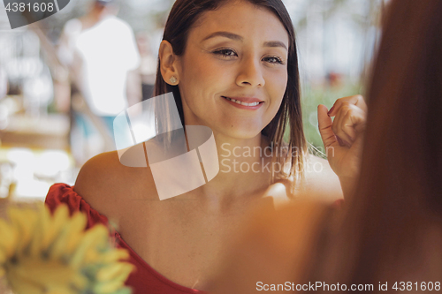Image of Smiling woman with friend in outside cafe
