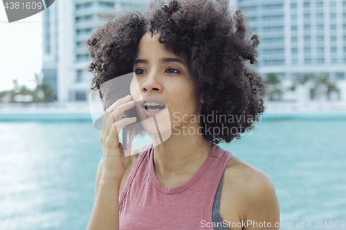 Image of Black girl having phone call on seafront