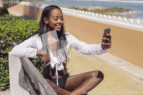 Image of Woman taking selfie on bench