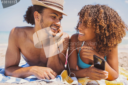 Image of Couple on beach listening to music and smiling