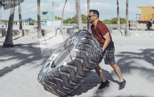 Image of Man working out with tyre