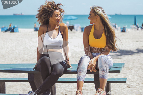 Image of Lounging girlfriends in sportswear on beach