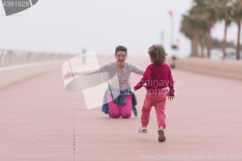 Image of mother and cute little girl on the promenade by the sea