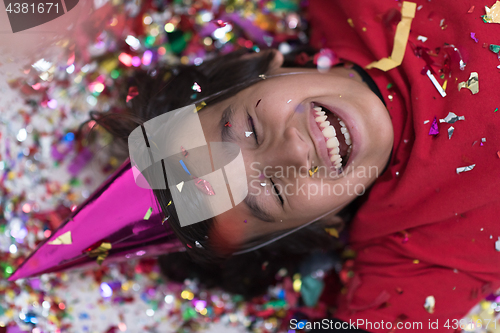 Image of kid blowing confetti while lying on the floor