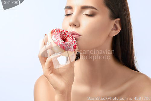 Image of beautiful woman biting a donut