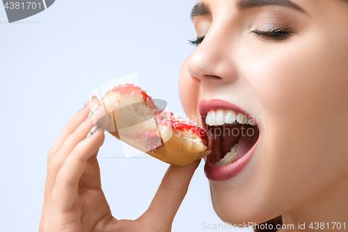 Image of beautiful woman biting a donut