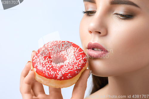 Image of beautiful woman biting a donut