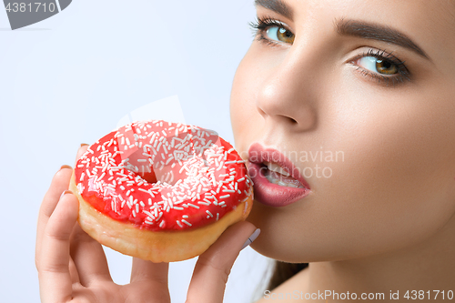 Image of beautiful woman biting a donut