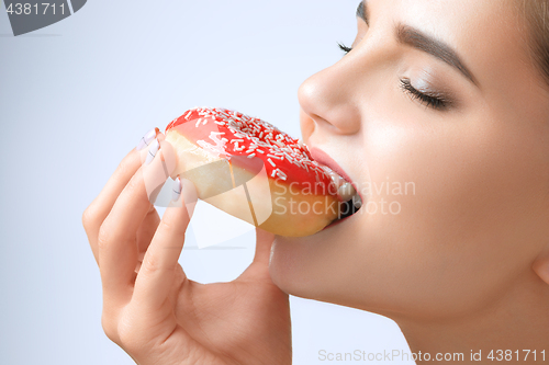 Image of beautiful woman biting a donut