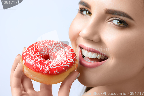 Image of beautiful woman biting a donut
